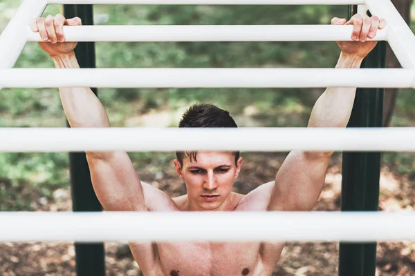 Muskulös ung man göra pull ups övningar på bar — Stockfoto