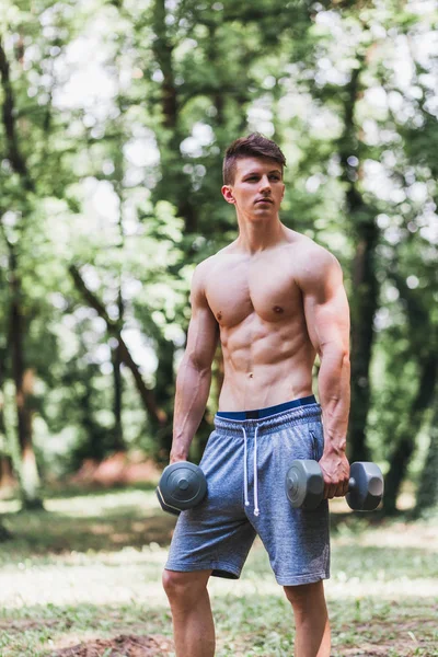 Joven musculoso posando con pesas —  Fotos de Stock