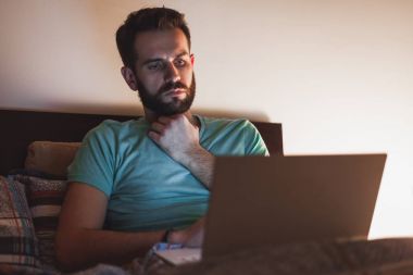 Genç adam yatakta geç çalışma