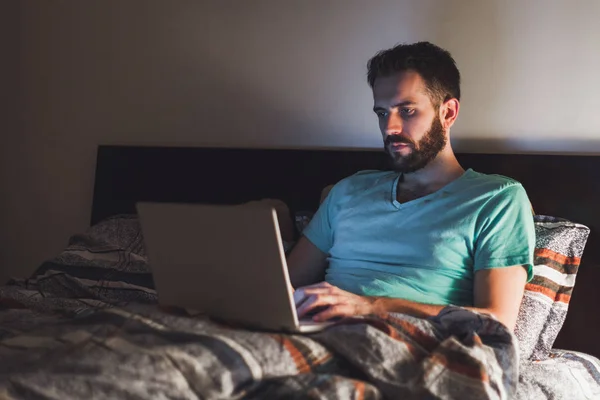 Young man working late in bed — Stock Photo, Image