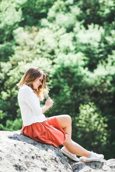 Mujer joven con flores en las manos — Foto de Stock