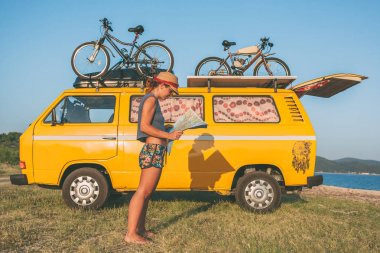 Summer holidays, road trip, vacation, travel and people concept - young hippie women in front of minivan car on beach