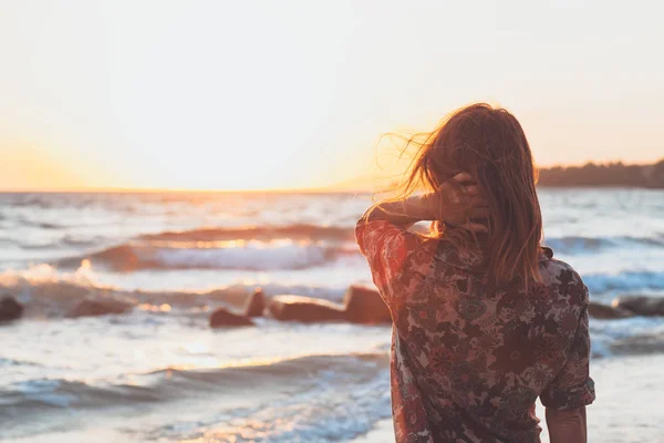 在海滩享受日落和波浪的年轻妇女 — 图库照片
