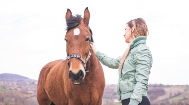Güzel genç kadın kahverengi bir atı ile bağ çiftlikte