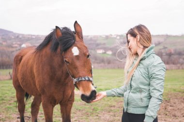 Güzel genç kadın kahverengi bir atı ile bağ çiftlikte