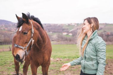 Güzel genç kadın kahverengi bir atı ile bağ çiftlikte