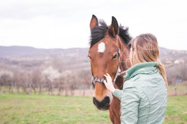 Güzel genç kadın kahverengi bir atı ile bağ çiftlikte