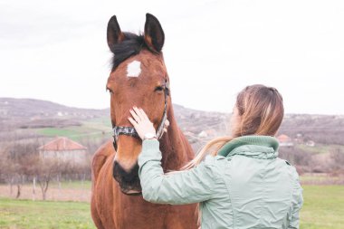 Güzel genç kadın kahverengi bir atı ile bağ çiftlikte