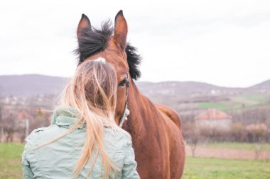 Güzel genç kadın kahverengi bir atı ile bağ çiftlikte