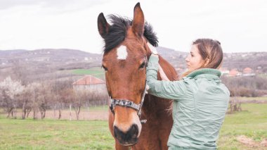 Güzel genç kadın kahverengi bir atı ile bağ çiftlikte
