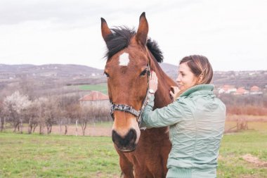 Güzel genç kadın kahverengi bir atı ile bağ çiftlikte