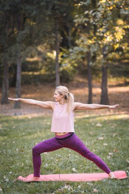 Sonbaharda parkta yoga yapan genç bir kadın.