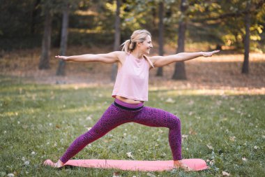 Sonbaharda parkta yoga yapan genç bir kadın.