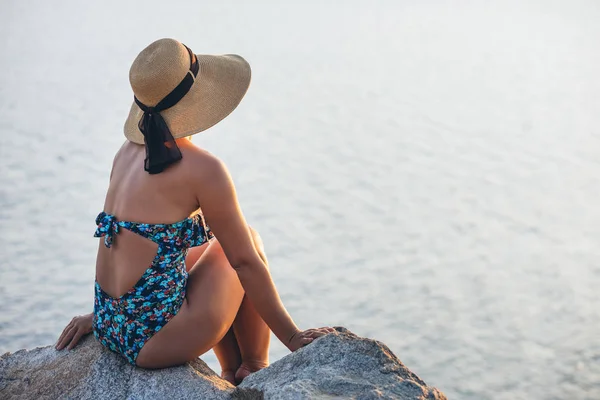 海辺の崖の上で夕日を楽しむ若い女性 — ストック写真