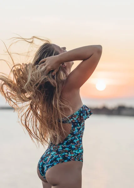 若いです女性でスイミングスーツ遊びとともに彼女の髪によって海で日没 — ストック写真