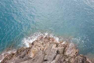Deniz dalgalarının tepesi kayalık kıyıya vuruyor.