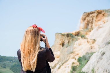Genç bayan gezgin doğada küçük bir şelalenin fotoğrafını çekiyor.