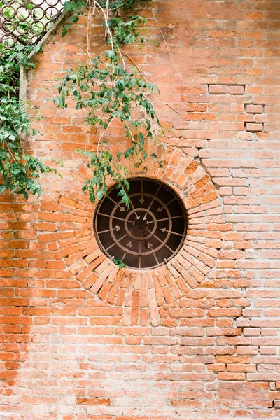 Old rustic wall with circular window in and old town in Italy