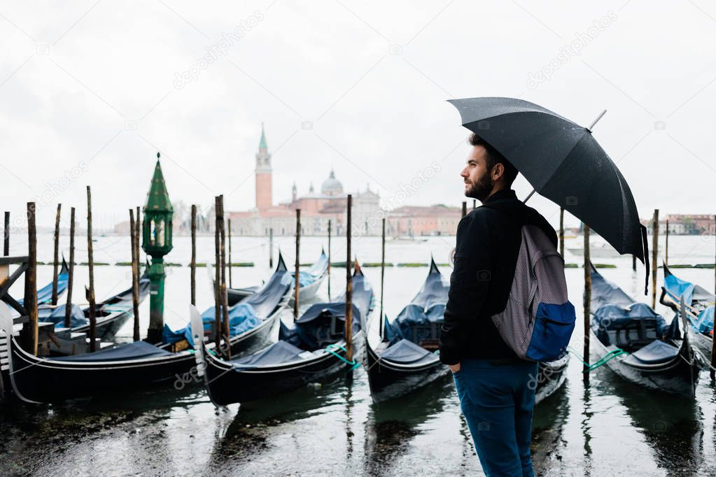 Young traveler in Venice, Italy standing by the canal on a rainy day