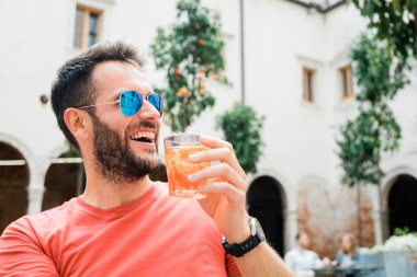 Yazın bir kafede oturan genç yakışıklı adam kahve ve kokteyl içiyor.