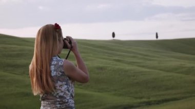 Genç bayan gezgin gün batımında güzel bir Toskana manzarasının fotoğrafını çekiyor.