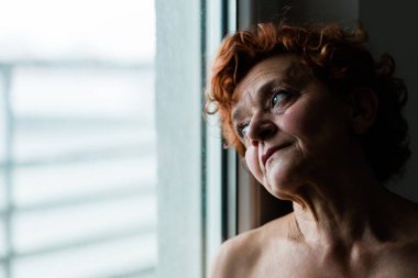 Pencerenin kenarındaki olgun kadın hayatı düşünüyor.