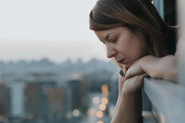 アパートのバルコニーから外を見る若い悲しい女性 — ストック写真