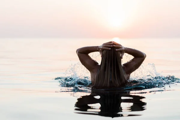 日落时在海里游泳的年轻女子 — 图库照片