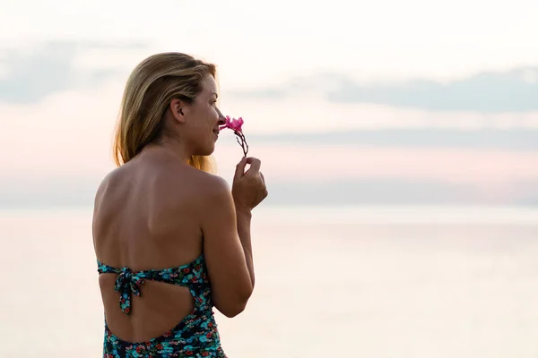 ビーチで夕日を楽しむ熱帯の花の香り若い女性 — ストック写真