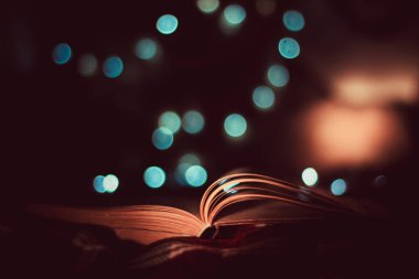 Arka planda bulanık ışıklar olan açık kitabın yakın çekim görüntüsü