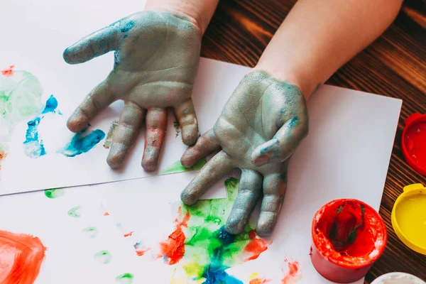 cropped shot of little kid painting papers with hands