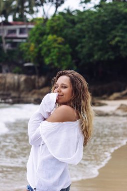 Kumsalda poz veren bronz tenli, beyaz, sarışın genç bir kadın. 