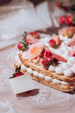 Gül ve çilek şeklinde bir kalp şeklinde beyaz kremalı kek. Not için şablon. Yakın plan.