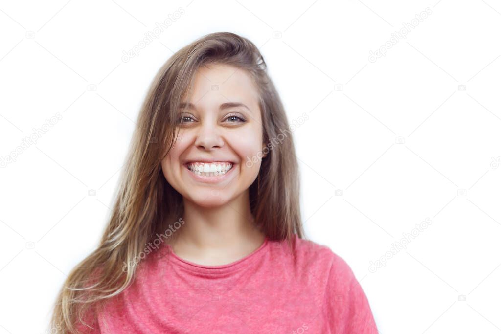 Portrait of a caucasian happy smiling girl in a pink t-shirt on an isolated white background. Real sincere emotions. Young woman with a beautiful smile. Even teeth of natural color