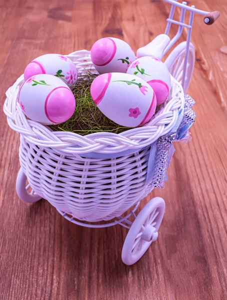 Çoklu renkli Paskalya yumurtalarıyla dolu sepeti olan üç tekerlekli oyuncak bisiklet..