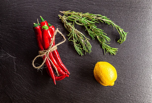 Kırmızı biber, biberiye, limon siyah şist yüzeyde servis edilir.