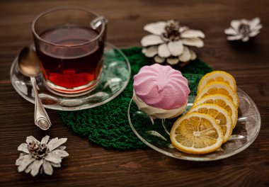 Marşmelov, limon dilimleri ve yeşil şifoniyerli eşarplı çay kompozisyonu ve yapay çiçekler.