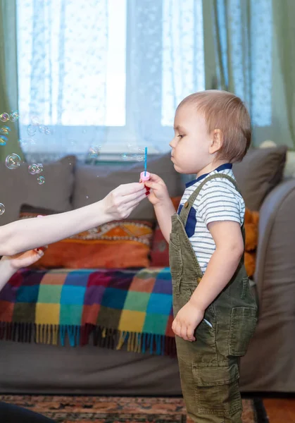 Küçük çocuk sabun köpüğü üflüyor.
