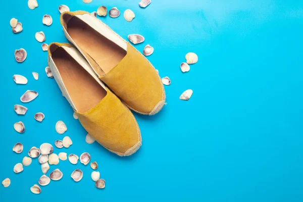 Mavi arkaplanda Espadrilles ve deniz kabukları kopyalama alanı