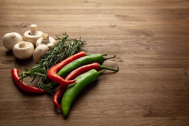 Çeşitli biberler, biberiye, sarımsak ve şampiyonlar ahşap masa üstünde fotokopi alanı ile