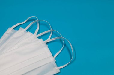 Coronavirus CoV-19 'u önleyin. Mavi arka planda beyaz tıbbi tek kullanımlık maskeler. Sosyal karantina, hijyen konsepti. Boşluğu kopyala.