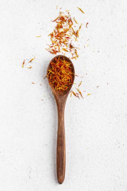 Tahta bir kaşıkta safran beyaz bir masanın üstüne serpilmiştir.