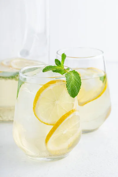Beyaz arka planda şeffaf bardaklarda limonlu, naneli ve buzlu su, yaz içecekleri, limonata