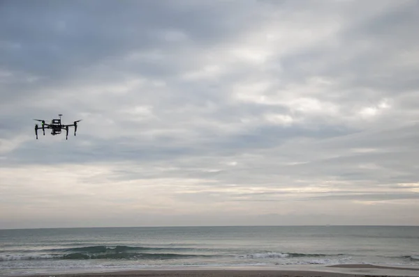 Drone with professional camera flying over the sea on a cloudy day. Drone hovering, new technology in the aero photo shooting.