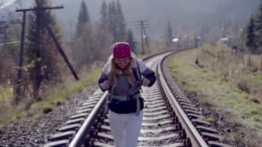 Kederli bir şekilde seyahat eden turist kız, macera arayışında, nehrin kenarında, ormanın içinden, dağın tepesine doğru yürüyor.