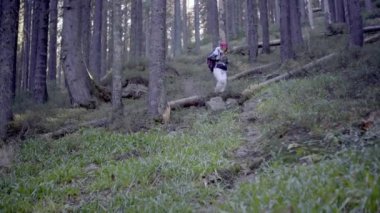 Kederli bir şekilde seyahat eden turist kız, macera arayışında, nehrin kenarında, ormanın içinden, dağın tepesine doğru yürüyor.