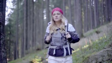 Kederli bir şekilde seyahat eden turist kız, macera arayışında, nehrin kenarında, ormanın içinden, dağın tepesine doğru yürüyor.