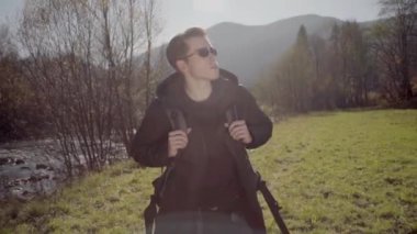 Kederli bir şekilde seyahat eden turist, macera arayışında, nehrin kenarında, ormanın içinde, dağın zirvesine doğru yürüyor.