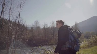 Kederli bir şekilde seyahat eden turist, macera arayışında, nehrin kenarında, ormanın içinde, dağın zirvesine doğru yürüyor.