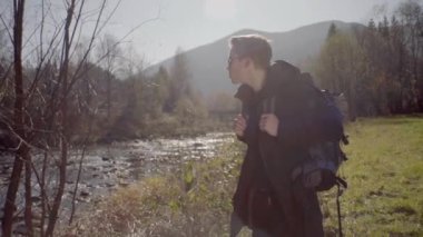 Kederli bir şekilde seyahat eden turist, macera arayışında, nehrin kenarında, ormanın içinde, dağın zirvesine doğru yürüyor.